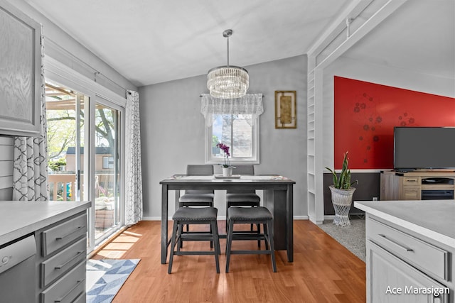 dining space featuring vaulted ceiling, a chandelier, light wood finished floors, and baseboards