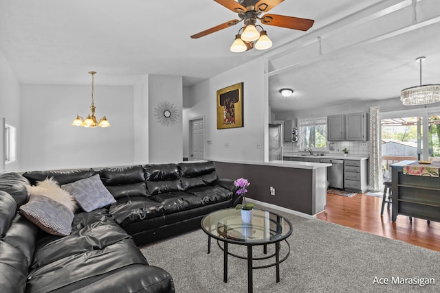 carpeted living room with a chandelier, ceiling fan, and a sink