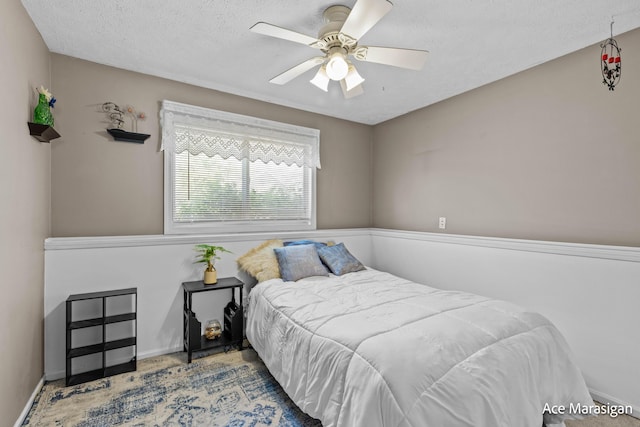 bedroom featuring a textured ceiling, ceiling fan, and baseboards