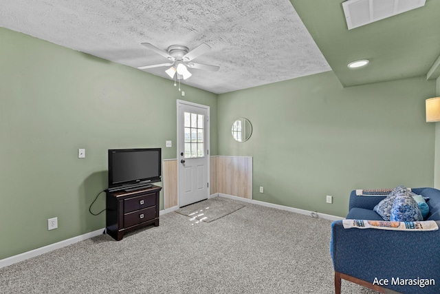 living area with ceiling fan, carpet flooring, a textured ceiling, and baseboards
