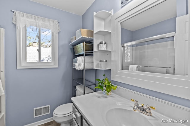 bathroom featuring a shower with shower door, toilet, vanity, and baseboards