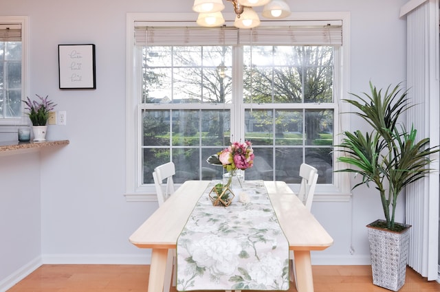 dining space with a chandelier, light wood-style floors, plenty of natural light, and baseboards