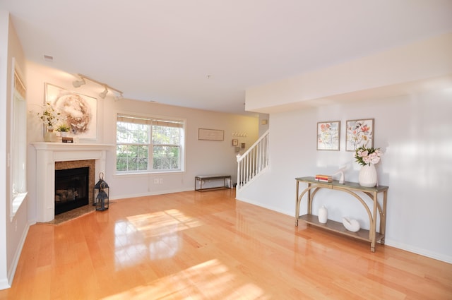 unfurnished living room with wood finished floors, stairway, a high end fireplace, and baseboards