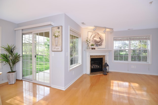unfurnished living room featuring wood finished floors, plenty of natural light, and a fireplace with flush hearth