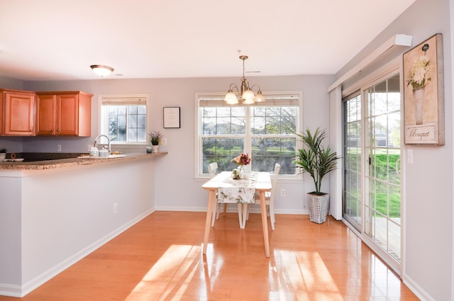 dining room with plenty of natural light, light wood-style flooring, a chandelier, and baseboards