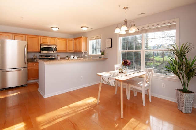kitchen featuring stainless steel appliances, light wood-style floors, light brown cabinetry, and a peninsula