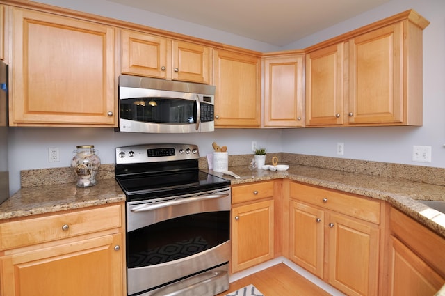 kitchen with stainless steel appliances, light wood finished floors, light brown cabinetry, and light stone counters