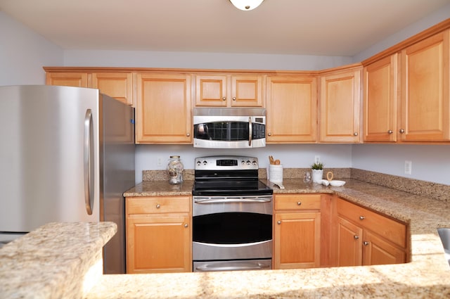 kitchen featuring stainless steel appliances, light brown cabinets, and light stone countertops