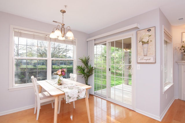 dining room with a chandelier, baseboards, and light wood-type flooring
