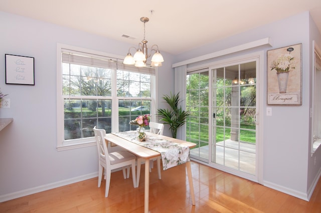 dining space with baseboards, a chandelier, and light wood finished floors
