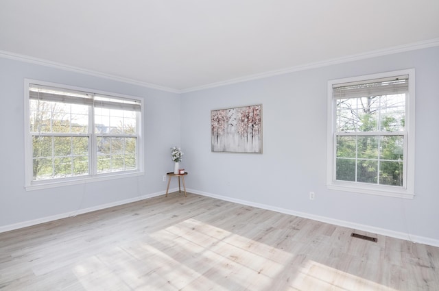 empty room featuring ornamental molding, light wood-type flooring, and baseboards