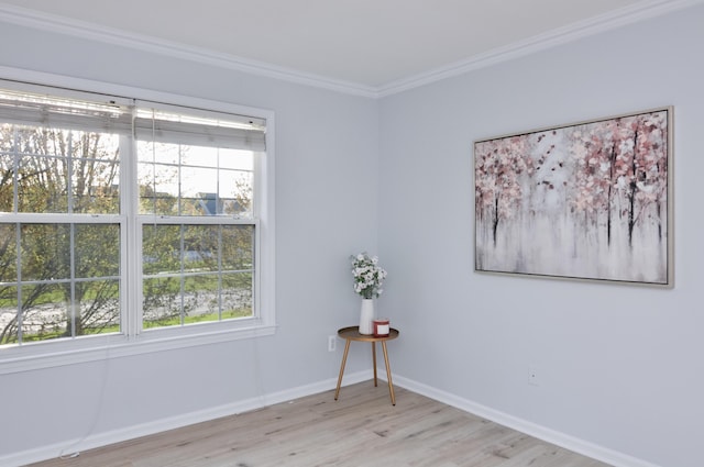 unfurnished room with healthy amount of natural light, light wood-type flooring, ornamental molding, and baseboards