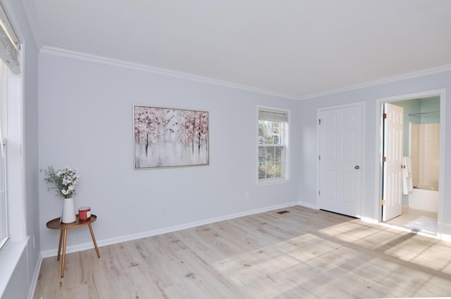 unfurnished bedroom with ornamental molding, light wood-style flooring, baseboards, and ensuite bathroom
