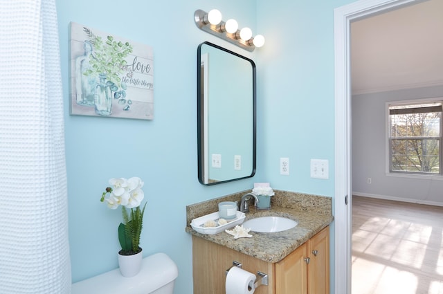 bathroom with toilet, vanity, ornamental molding, and baseboards