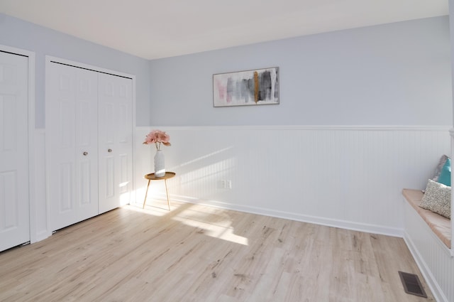 unfurnished bedroom with wood finished floors and wainscoting