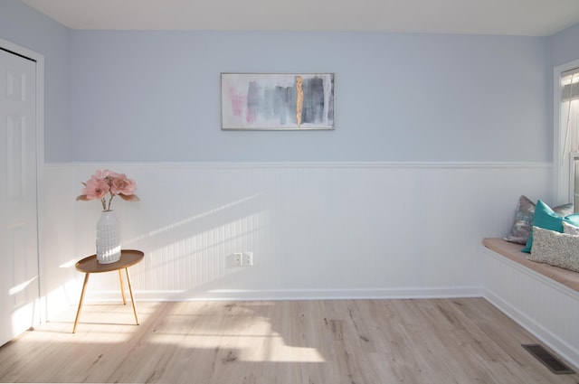 unfurnished room with wood finished floors and a wainscoted wall