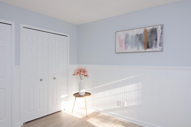 unfurnished bedroom with a wainscoted wall and wood finished floors