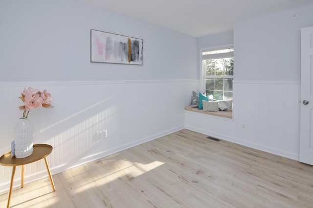 spare room with wainscoting, wood finished floors, and baseboards