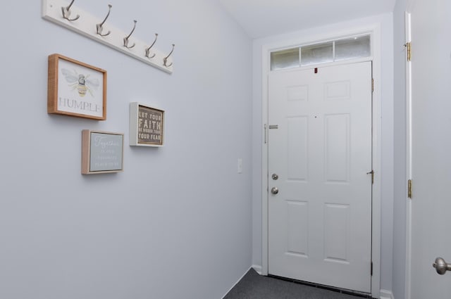 doorway with baseboards and carpet flooring