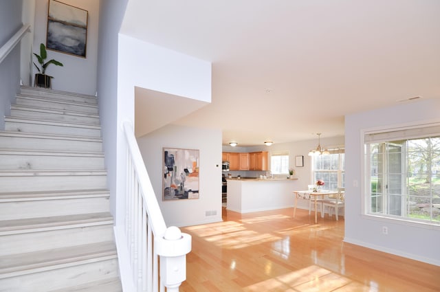 stairway featuring wood finished floors, a chandelier, and baseboards