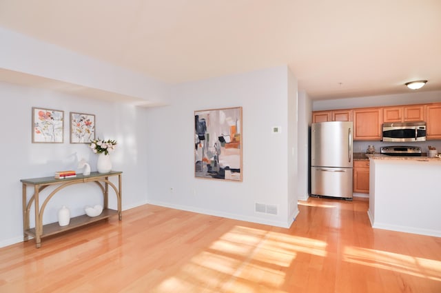 kitchen with appliances with stainless steel finishes, light wood finished floors, baseboards, and light countertops