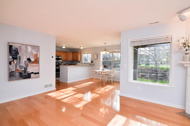 living area with a chandelier, light wood-style floors, and baseboards