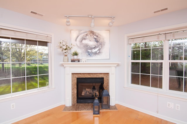 unfurnished living room featuring light wood finished floors, track lighting, and baseboards