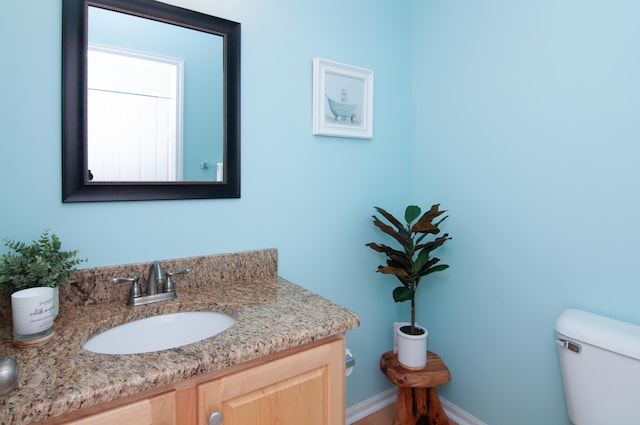 bathroom featuring toilet, vanity, and baseboards
