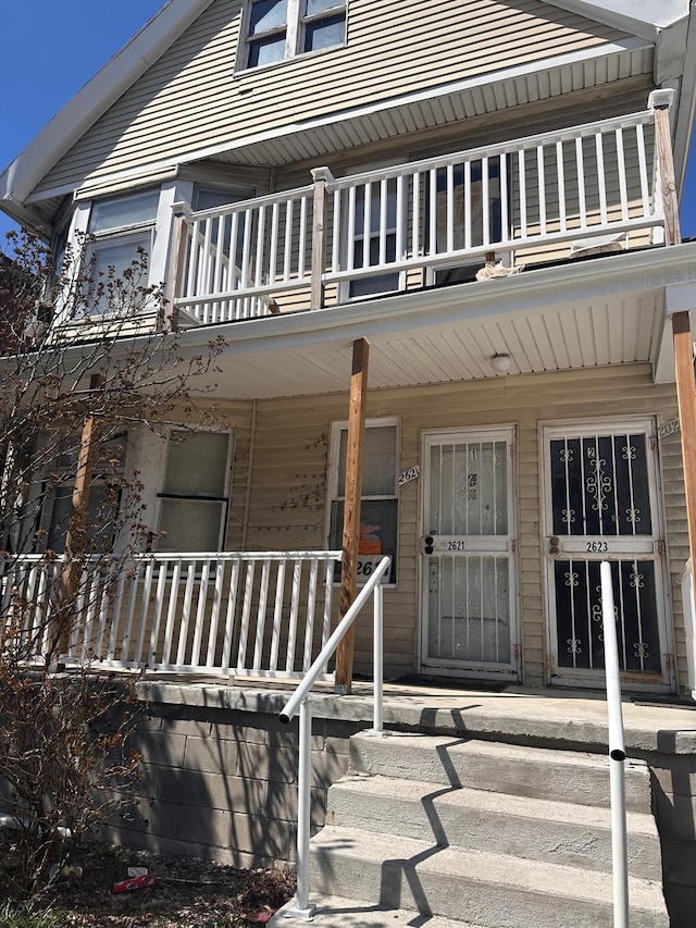 view of exterior entry with a balcony and a porch