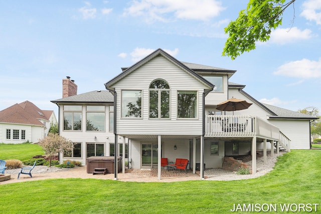 rear view of property featuring a hot tub, a patio area, a deck, a yard, and roof with shingles