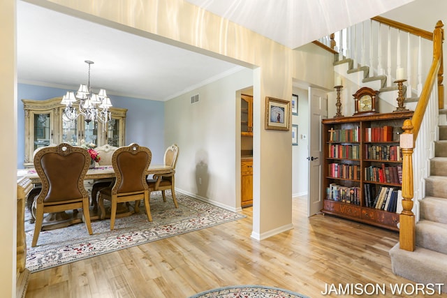 dining room featuring stairway, a chandelier, wood finished floors, ornamental molding, and baseboards