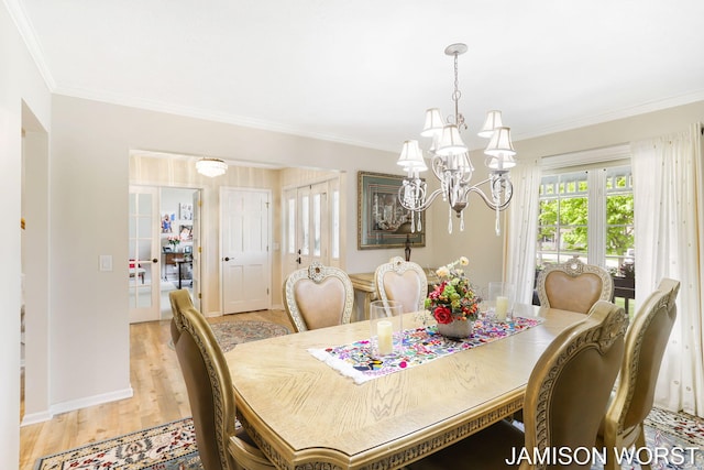 dining room with a chandelier, ornamental molding, light wood finished floors, and baseboards