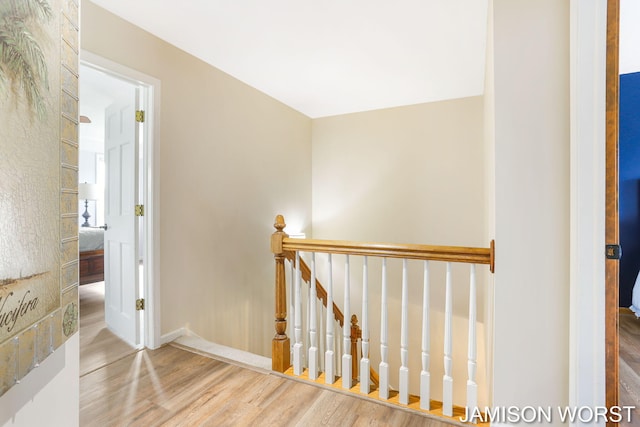 hall featuring an upstairs landing, wood finished floors, and baseboards