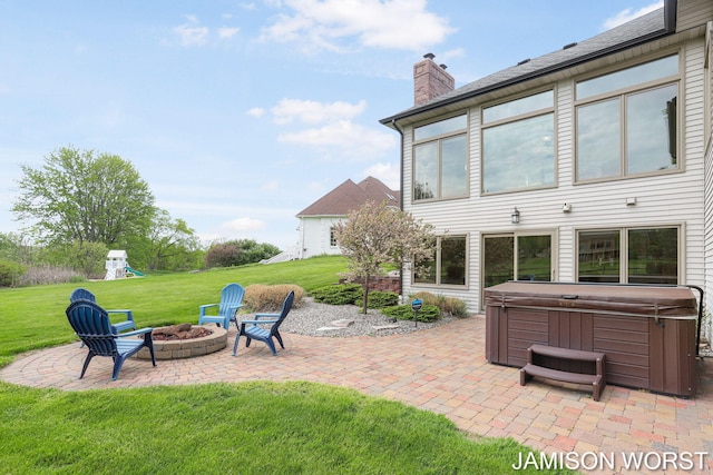 view of patio / terrace with a hot tub, a fire pit, and a playground