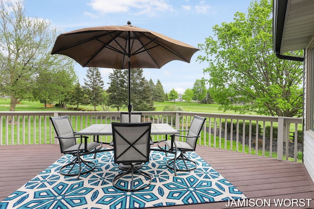 wooden terrace featuring outdoor dining space and a yard