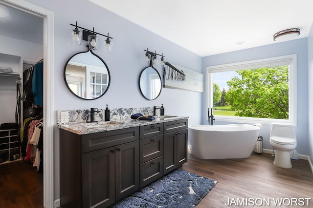 full bath featuring wood finished floors, a freestanding bath, and double vanity