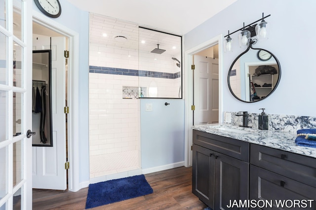 full bath with a walk in shower, wood finished floors, a walk in closet, and vanity