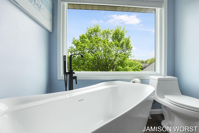 bathroom featuring plenty of natural light, toilet, and a freestanding bath