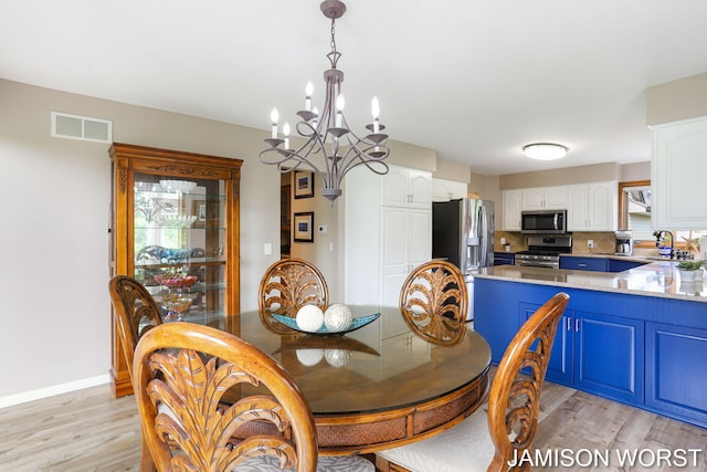 dining area with a chandelier, light wood finished floors, and baseboards