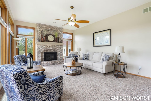 carpeted living area with plenty of natural light, baseboards, ceiling fan, and a brick fireplace