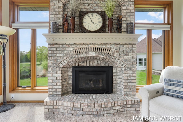 detailed view of a brick fireplace, baseboards, and carpet flooring