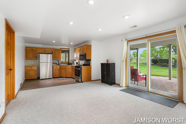 kitchen with appliances with stainless steel finishes, light colored carpet, baseboards, brown cabinets, and recessed lighting