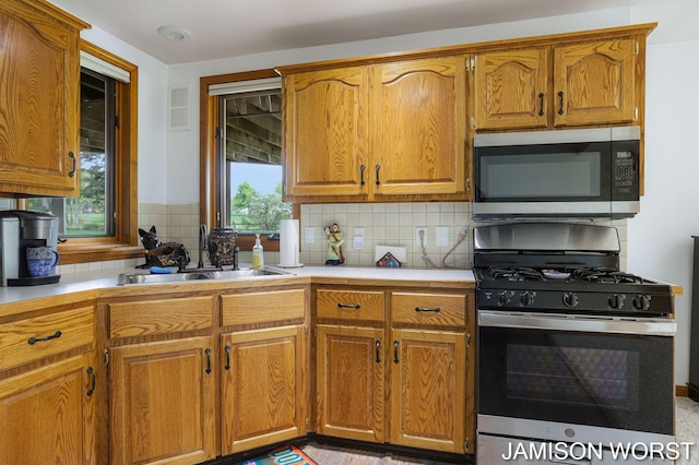 kitchen featuring appliances with stainless steel finishes, a sink, tasteful backsplash, and light countertops