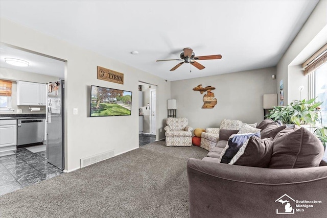 living room with plenty of natural light, a ceiling fan, and baseboards