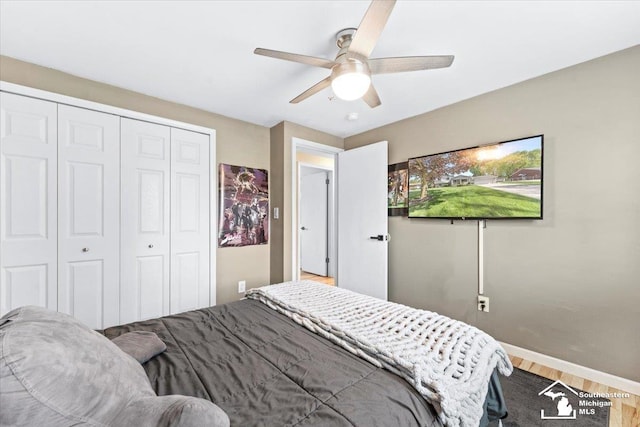 bedroom with wood finished floors, a closet, ceiling fan, and baseboards