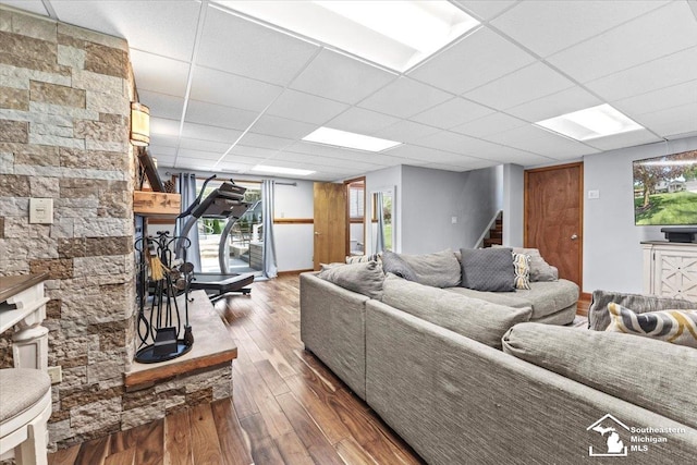 living room featuring wood-type flooring, stairs, and a drop ceiling