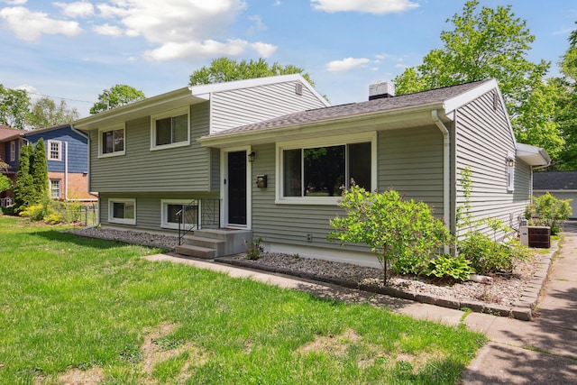 tri-level home featuring a chimney, a front lawn, and cooling unit