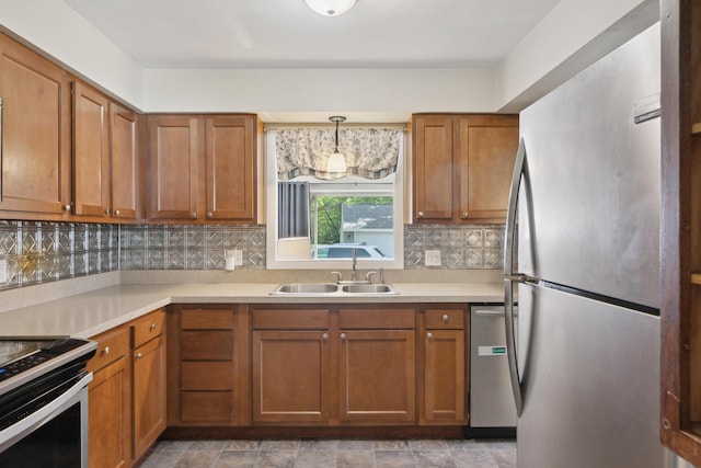 kitchen featuring appliances with stainless steel finishes, brown cabinets, decorative backsplash, a sink, and light countertops