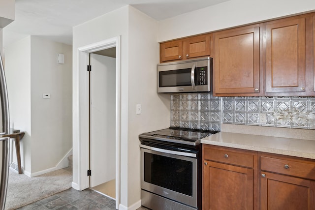 kitchen featuring appliances with stainless steel finishes, brown cabinets, light countertops, and backsplash
