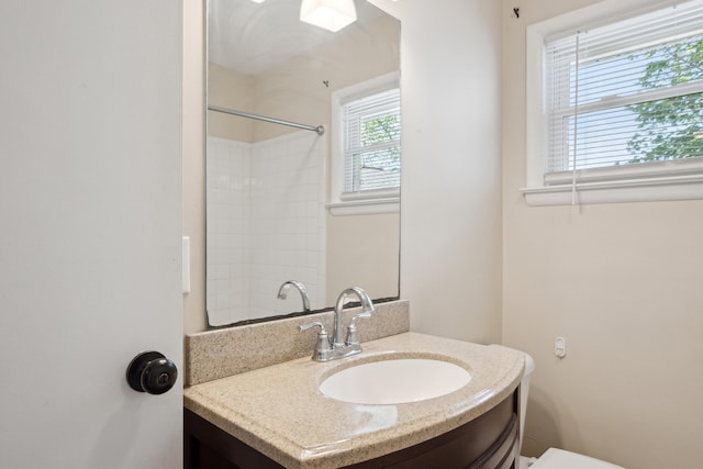 bathroom featuring vanity, a shower, and toilet